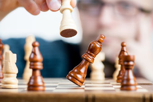 Man Holding Chess Piece over a chess board