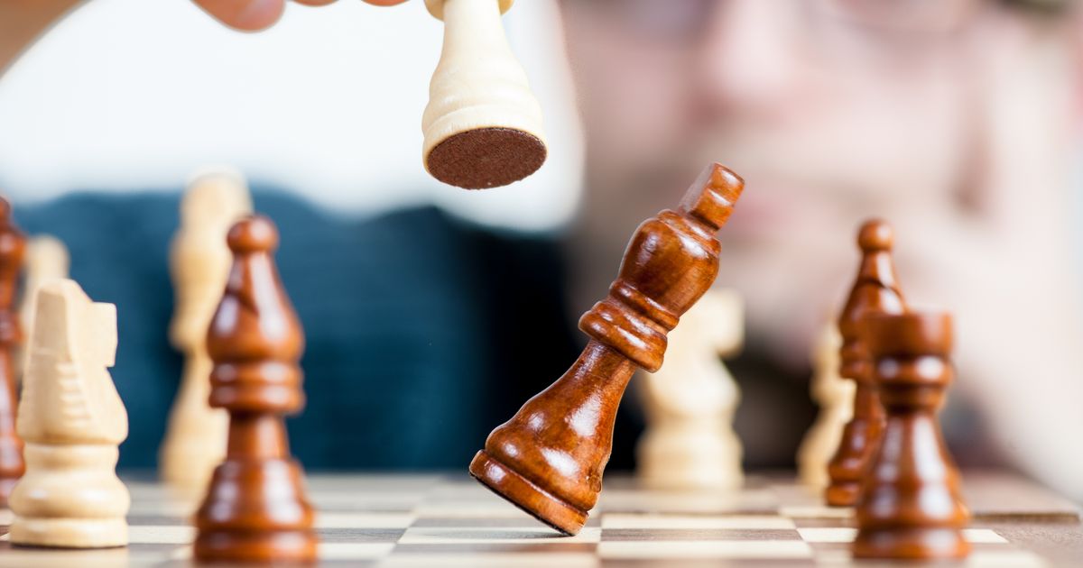 Close-up of a chess game with a focused player studying the board