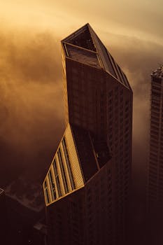 日落时分，一座未来派的摩天大楼在浓雾中浮现于现代城市