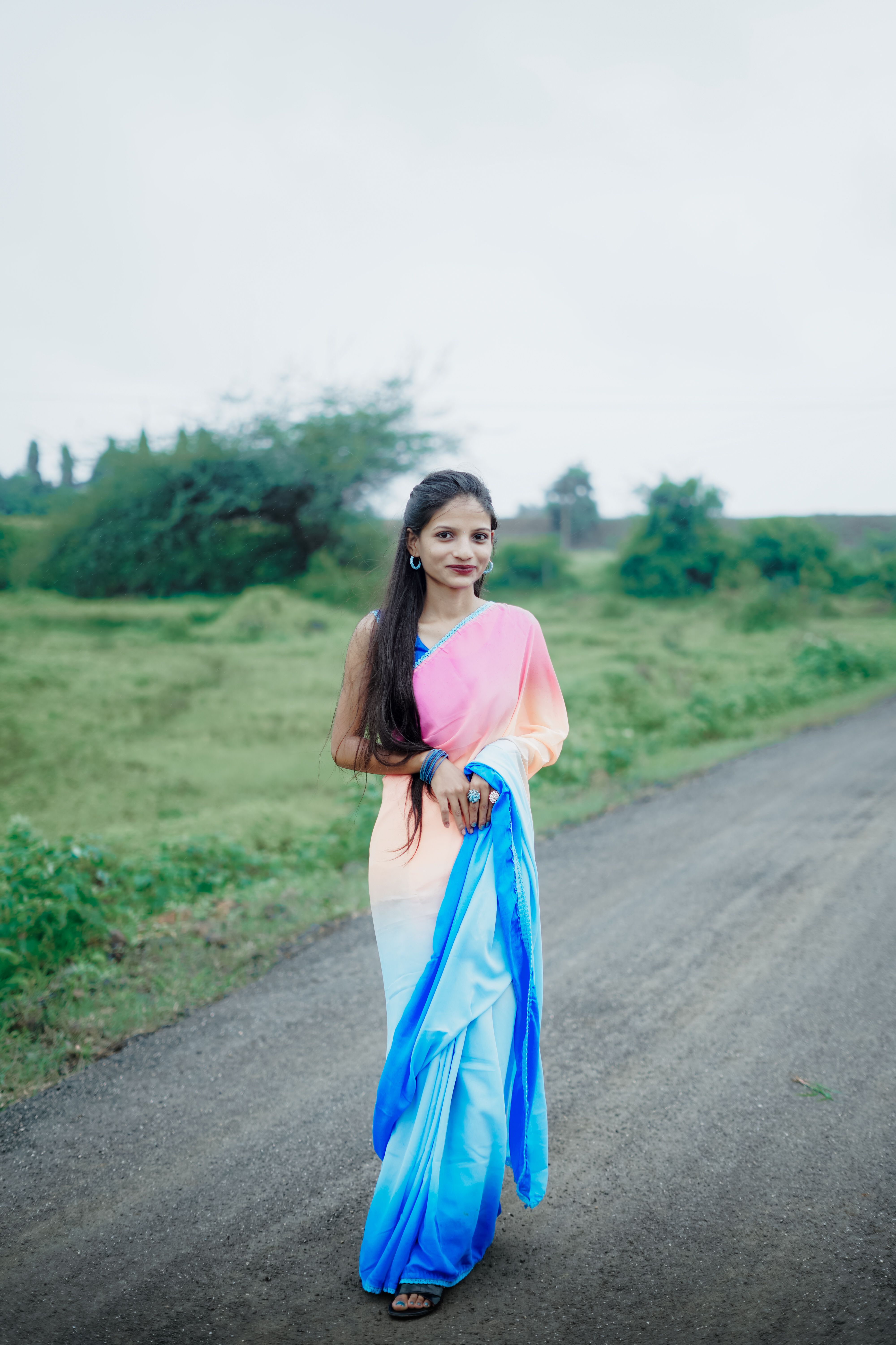 A woman in a blue and pink sari walking down a road · Free Stock Photo