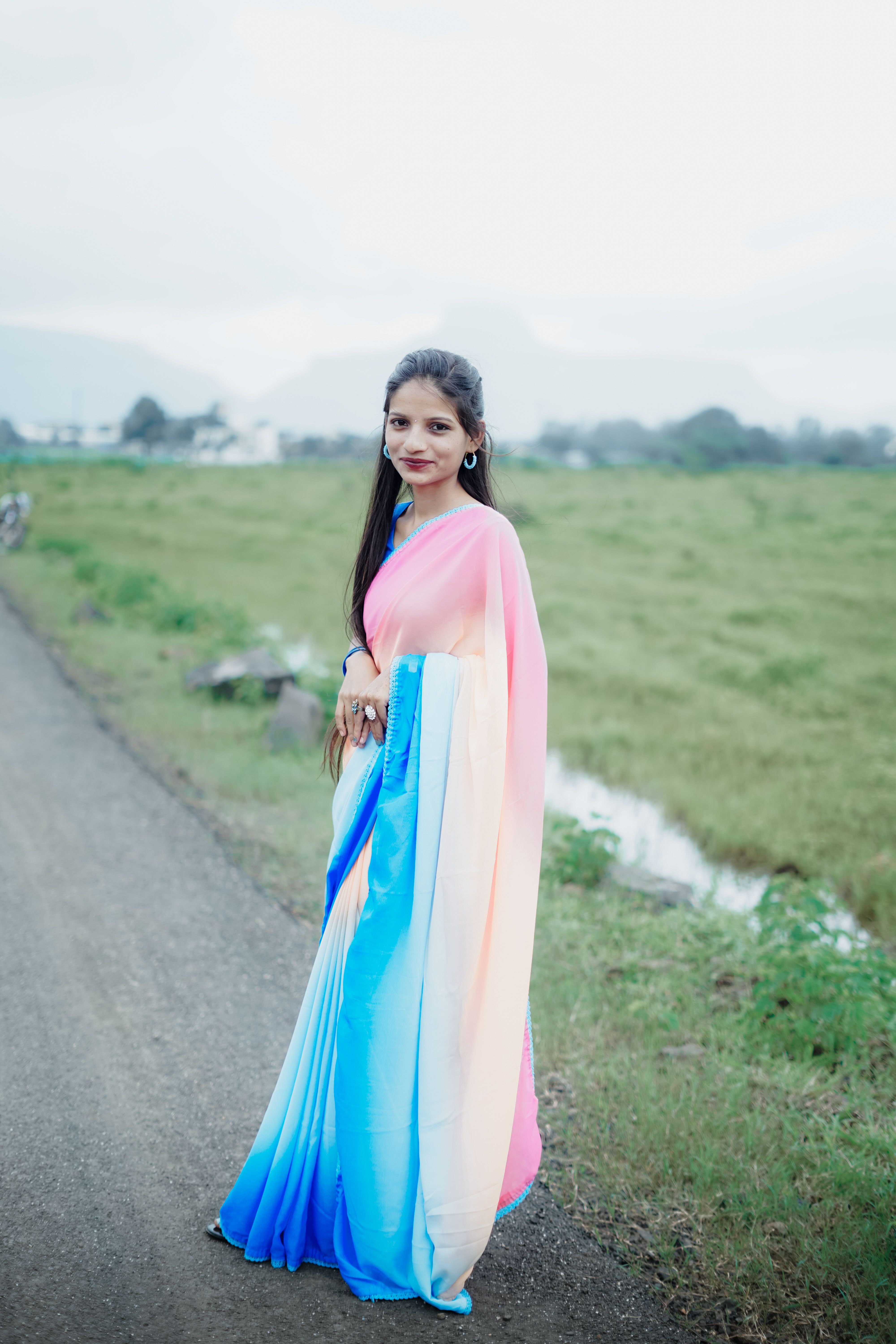 A beautiful woman in a colorful sari standing on a road · Free Stock Photo