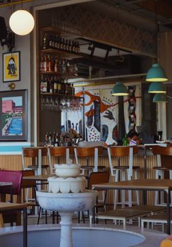 A stylish, modern bar interior with elegant seating, vibrant art and warm lighting.