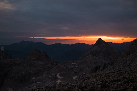 A stunning view of mountain peaks silhouetted against a vibrant dawn sky in Slovenia's Julian Alps.