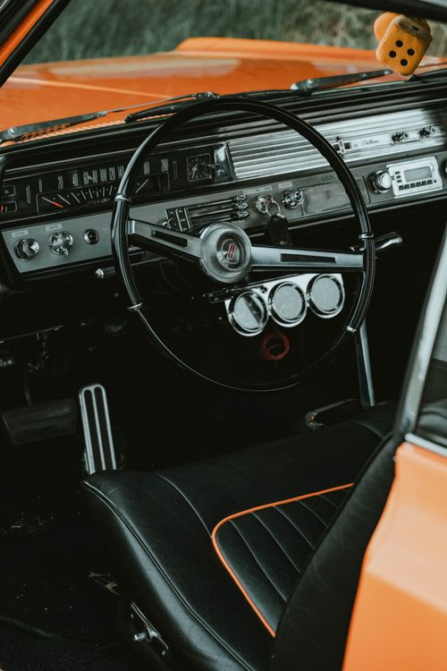 Free Explore the classic interior of a vintage orange muscle car, showcasing chrome details and luxury features. Stock Photo