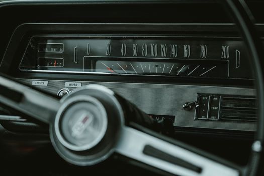 Close-up view of a classic car's dashboard, featuring an analog speedometer and steering wheel.