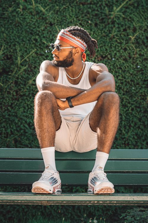 Free Fashionable adult man in casual attire sitting on a bench, soaking up the sun. Stock Photo