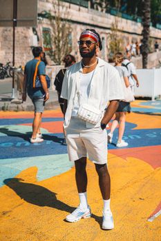Fashionable man posing with confidence on a vibrant painted street in a city.