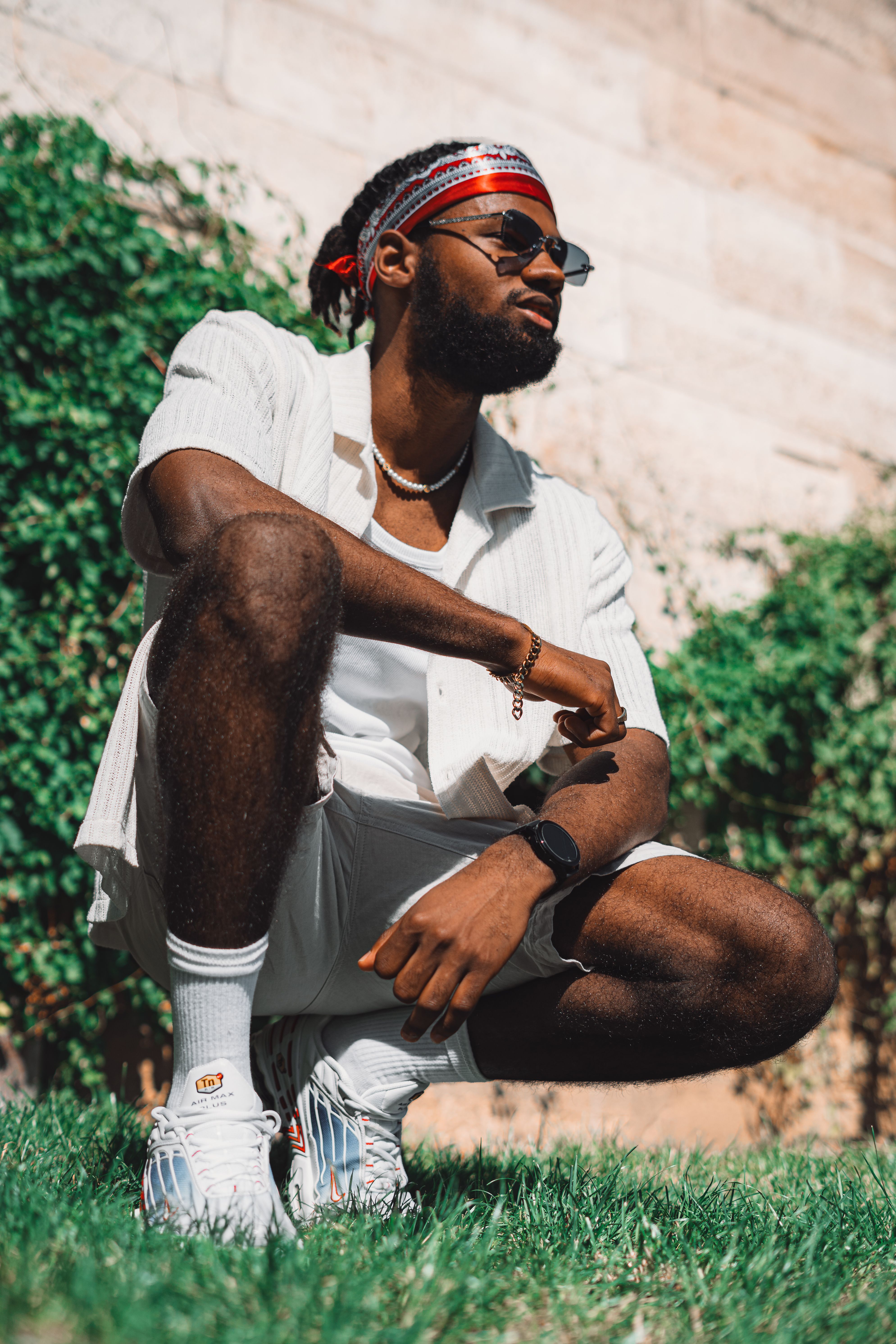 A fashionable man in sunglasses sitting outdoors, exuding confidence and style.