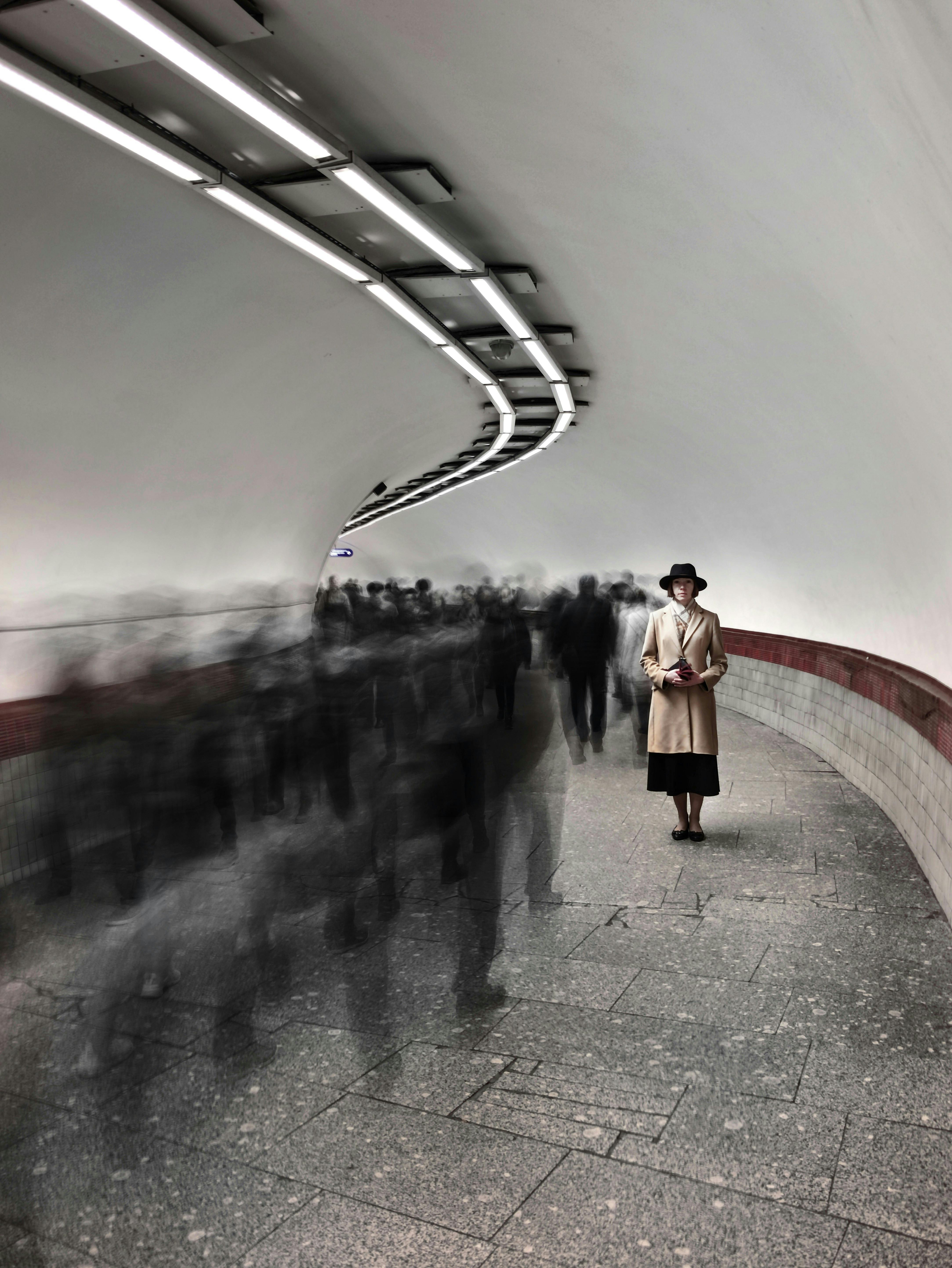 A lone woman stands amidst blurred motion in a crowded Saint Petersburg subway tunnel.