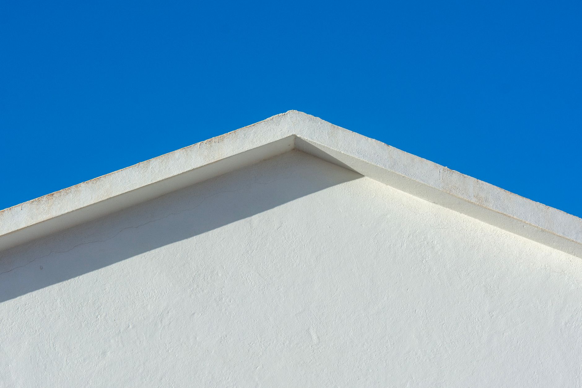 white stucco building roofline against a vivid blue Arizona sky representing cool roof reflectivity