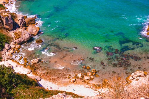 Free Scenic aerial shot of a serene beach with turquoise waters and rocky coastline. Stock Photo