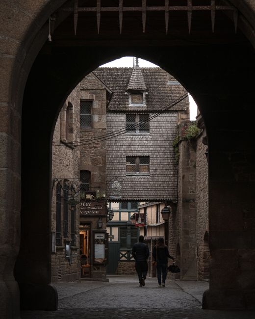 Explore Mont Saint-Michel through its iconic medieval architecture, captured outdoors with people walking.