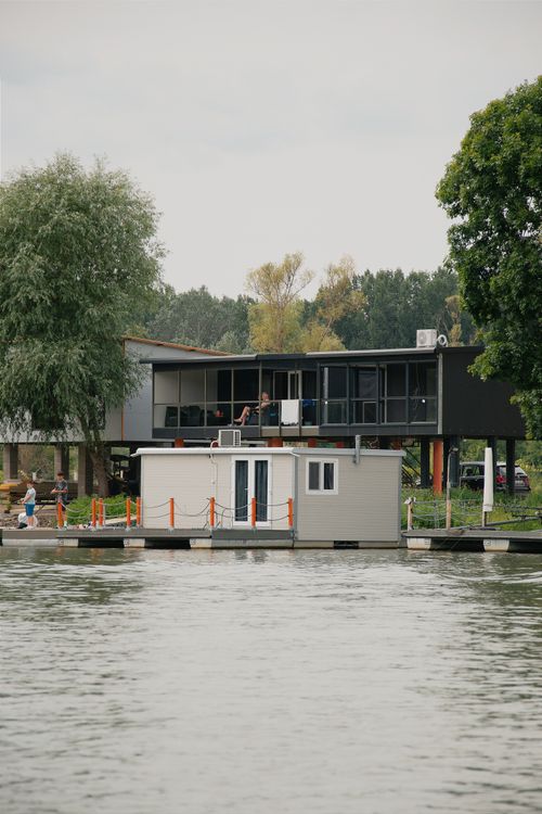 Free Modern building by a canal in Hungary with lush trees and calm water view. Stock Photo