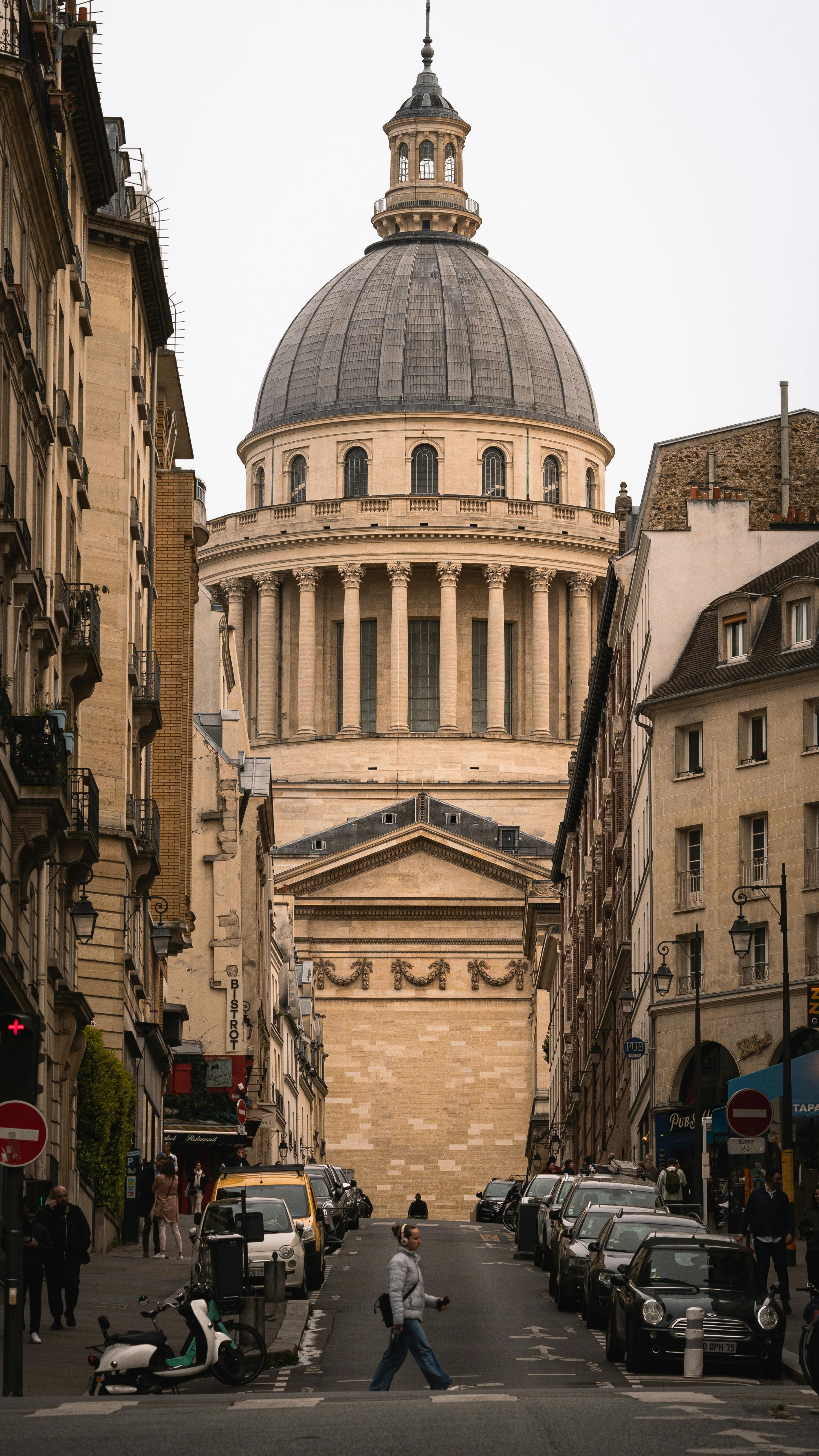 View of the Panthéon dome from a bustling Paris street, showcasing classical architecture.