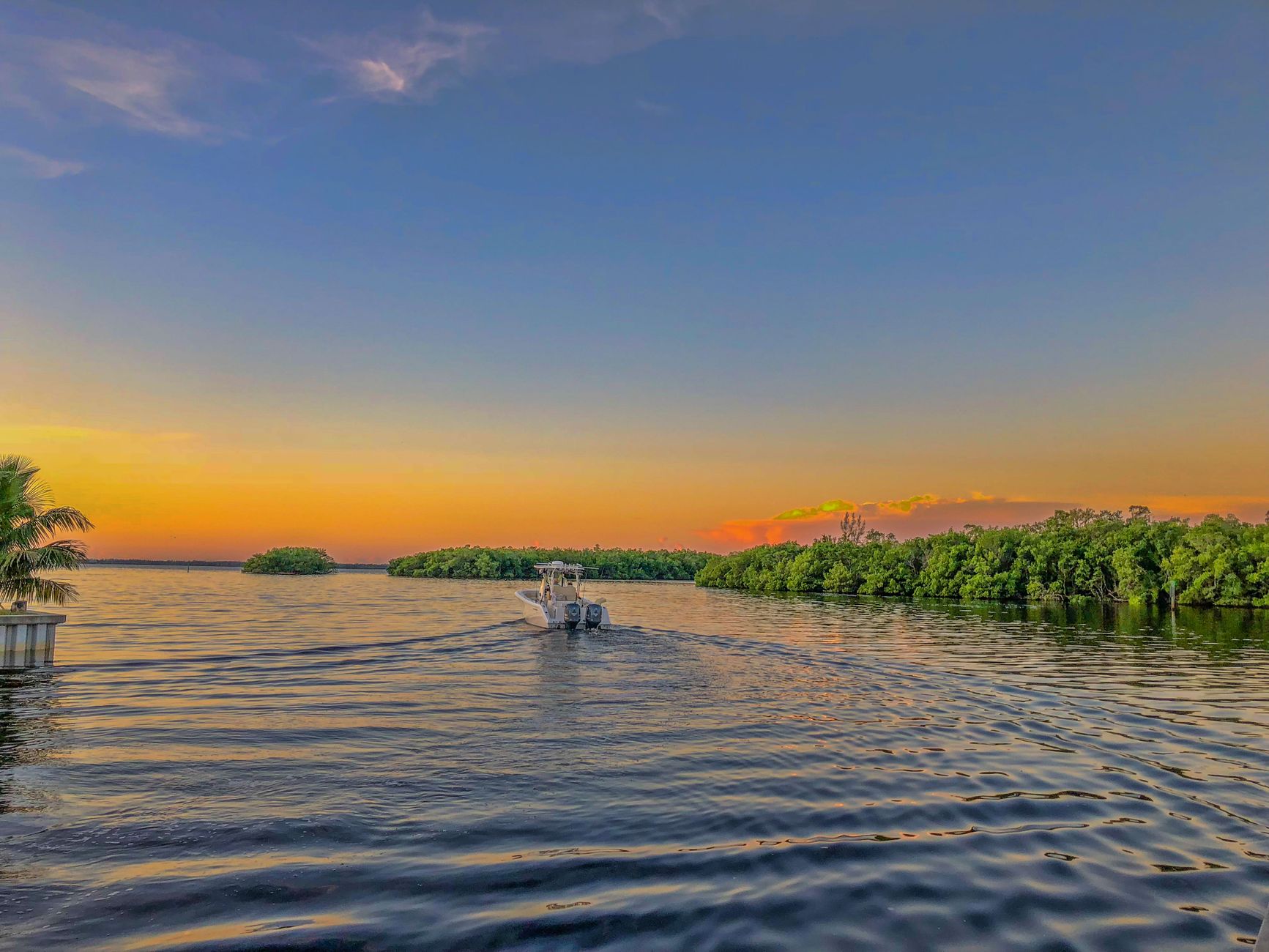 A tranquil boat ride during sunset over scenic waters in Florida, showcasing beautiful colors and calm surroundings.