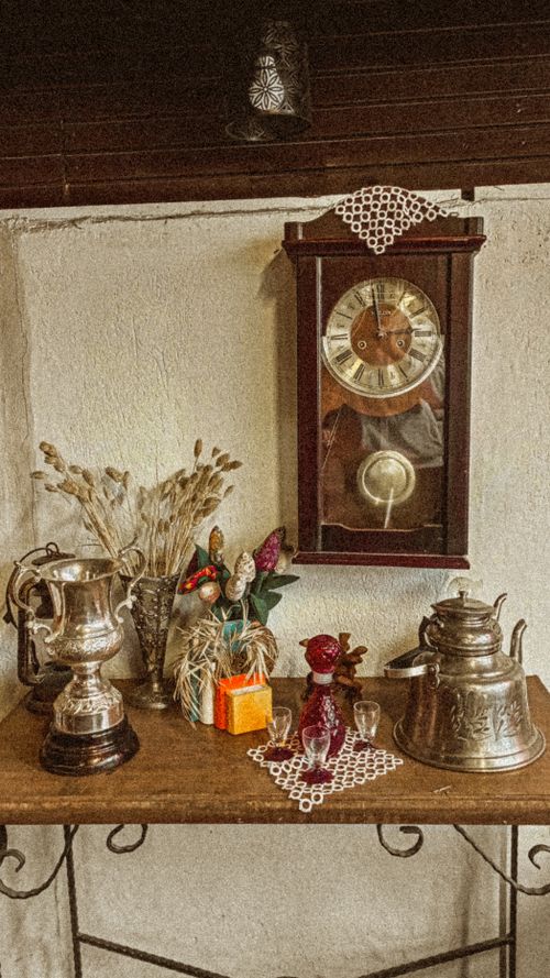 Free A classic arrangement featuring an antique wooden clock, teapot, and brass elements on a wooden table. Stock Photo