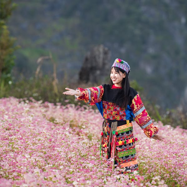 Happy Brunette Woman in Traditional Hmong Clothes Standing Among Flowers