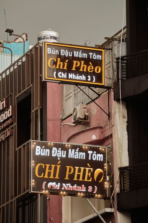 Free Urban Vietnamese restaurant signs for Chí Phèo showcasing vibrant street commerce. Stock Photo