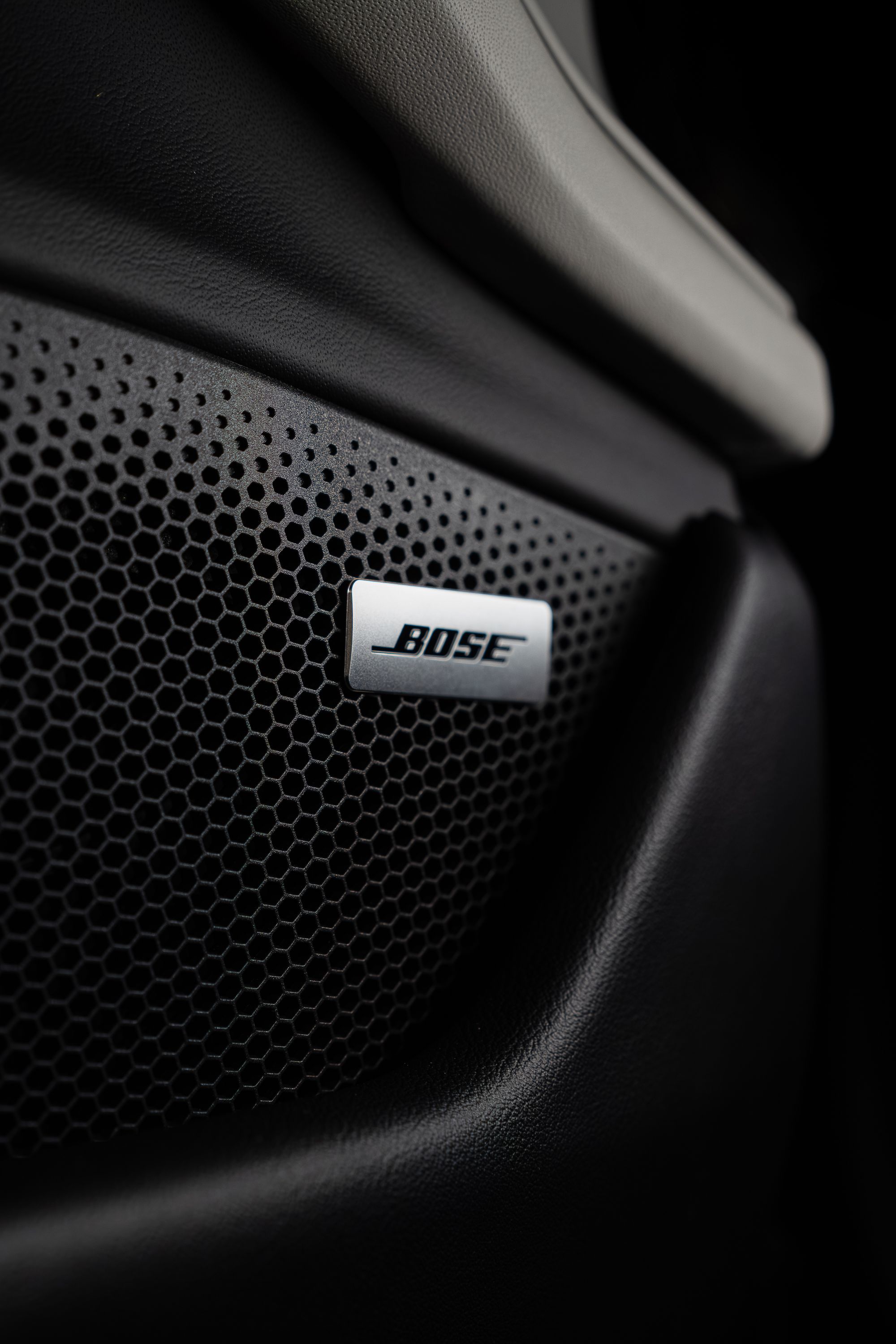 A Bose-badged in-car speaker grille directly illustrates a named factory audio brand tier visible on window stickers.