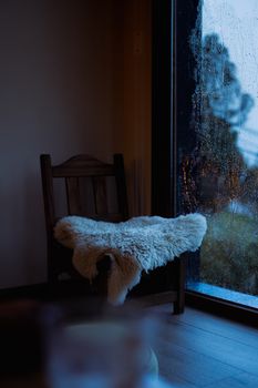 Warm interior view of a chair by a rain-soaked window in Bariloche, Argentina.