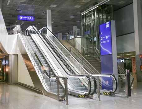 Contemporary airport terminal with empty escalator and clear signage indicating direction.