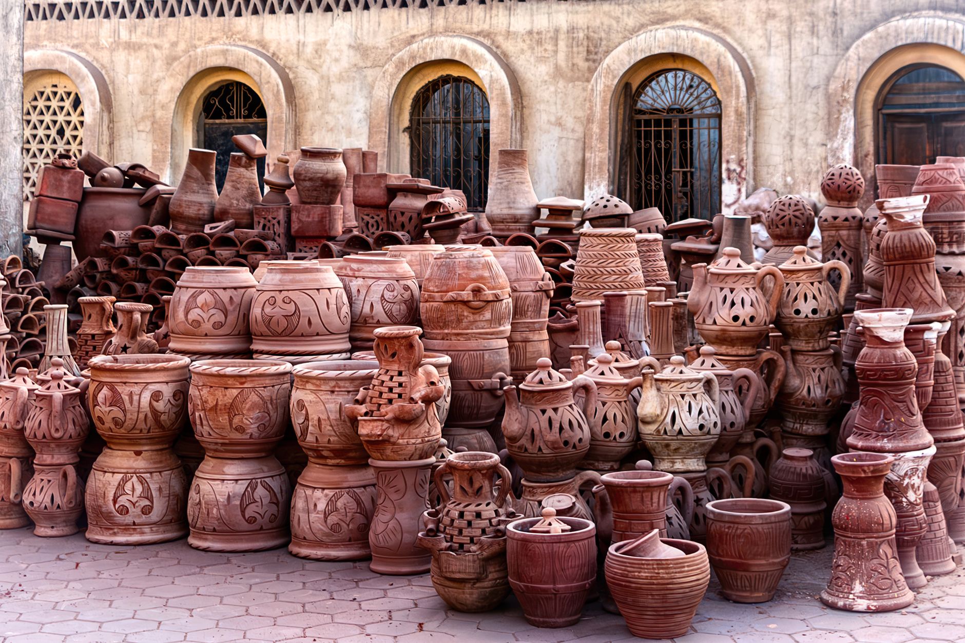 A diverse collection of traditional handmade pottery displayed outdoors, showcasing various styles and craftsmanship.