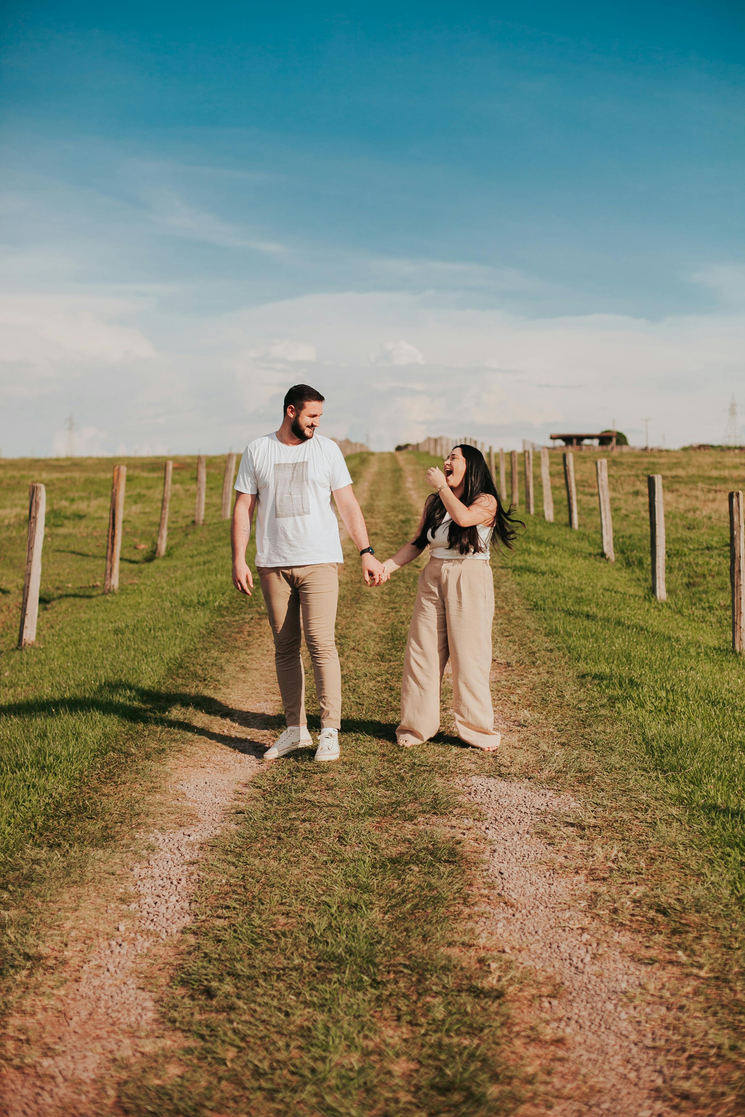 a couple holding hands walking down a dirt road