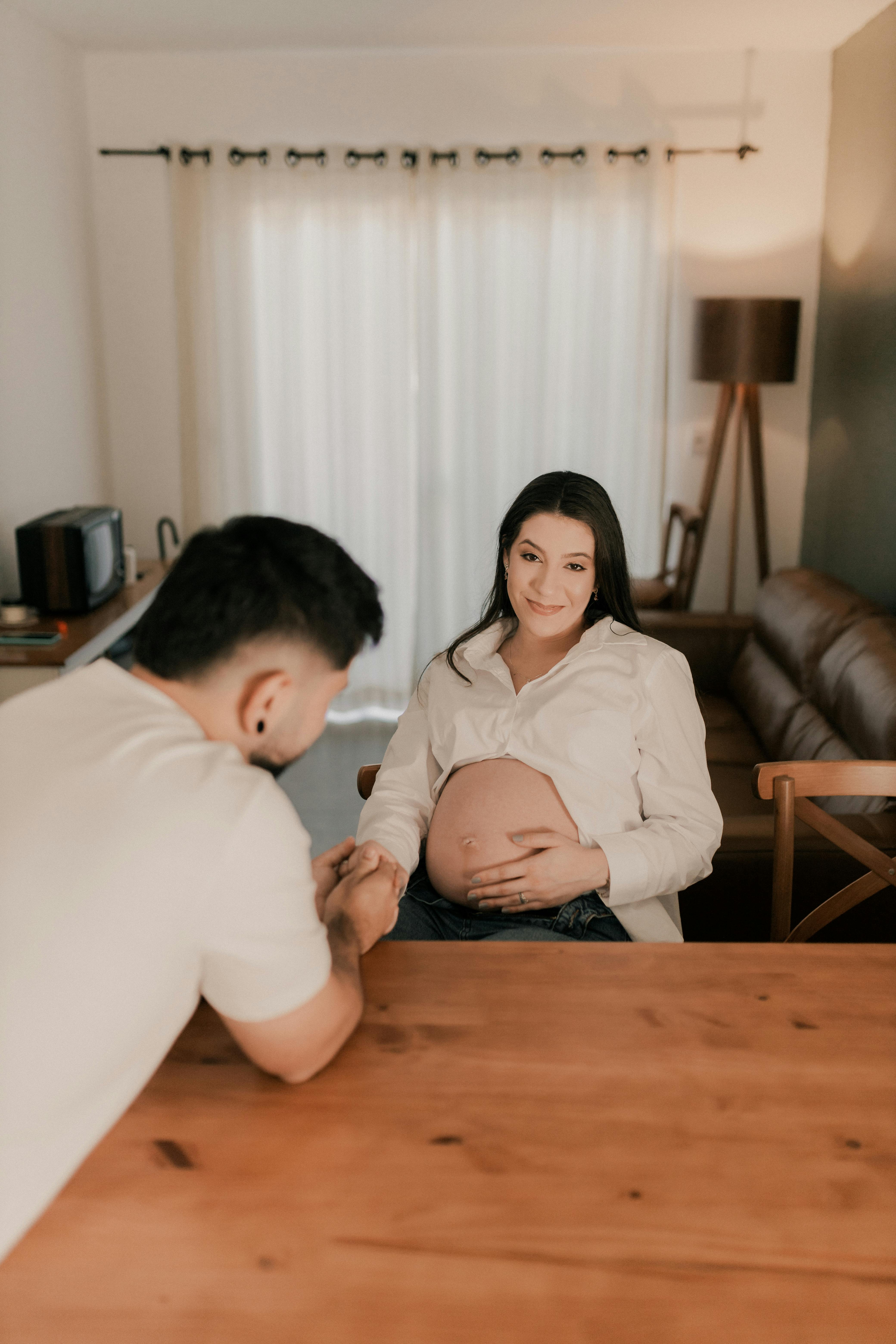 a man and woman sitting at a table with a pregnant woman