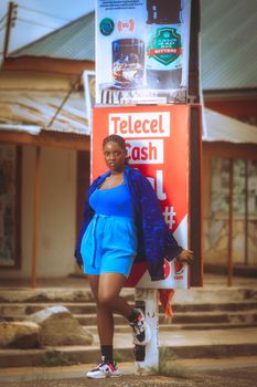Stylish woman in blue outfit posing by colorful street signage.