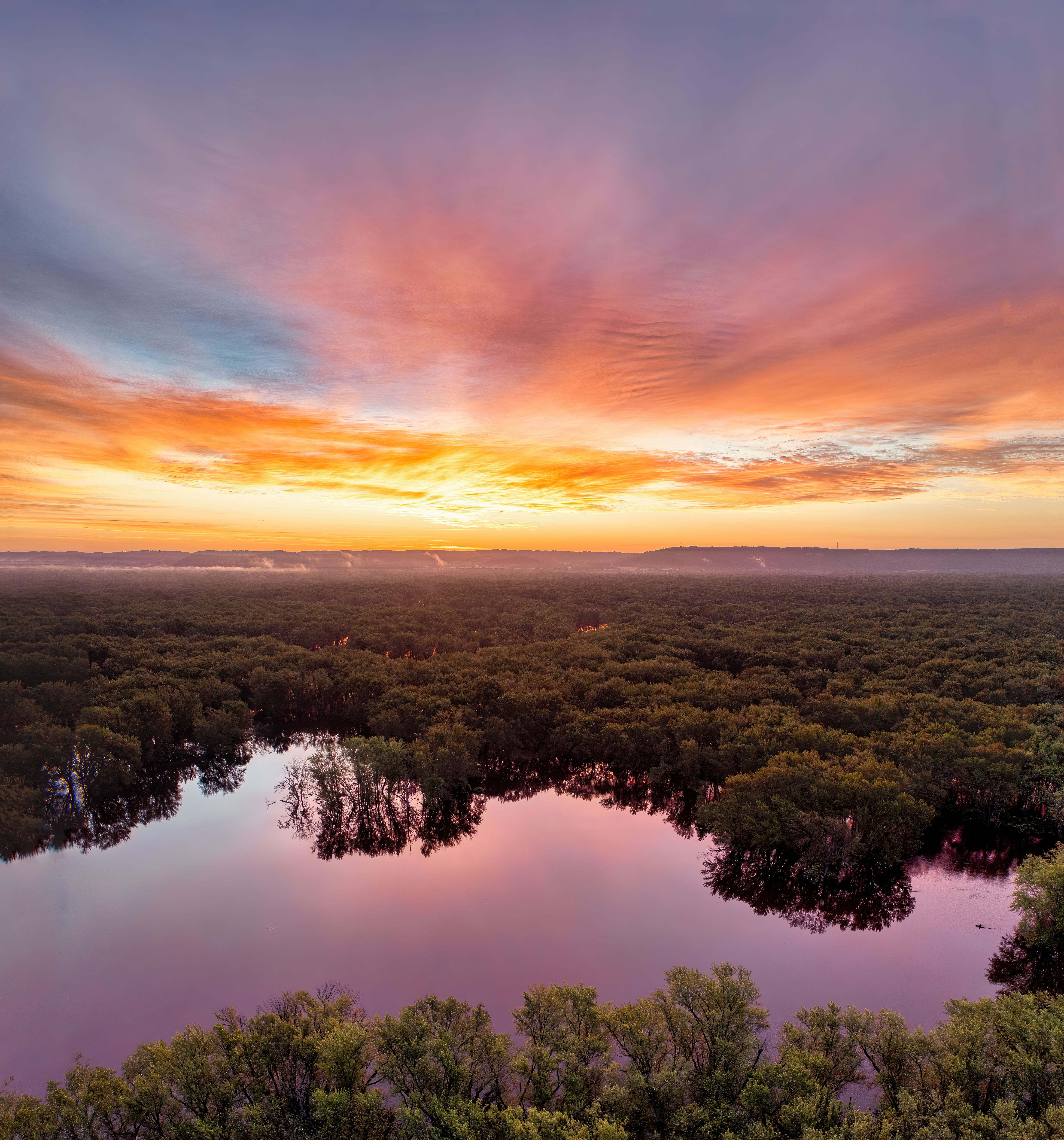 A sunset over a lake with trees and water · Free Stock Photo