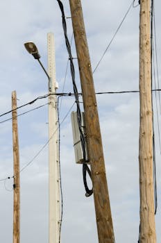 Wooden and steel power poles with wires against cloudy sky in Teruel, Spain.