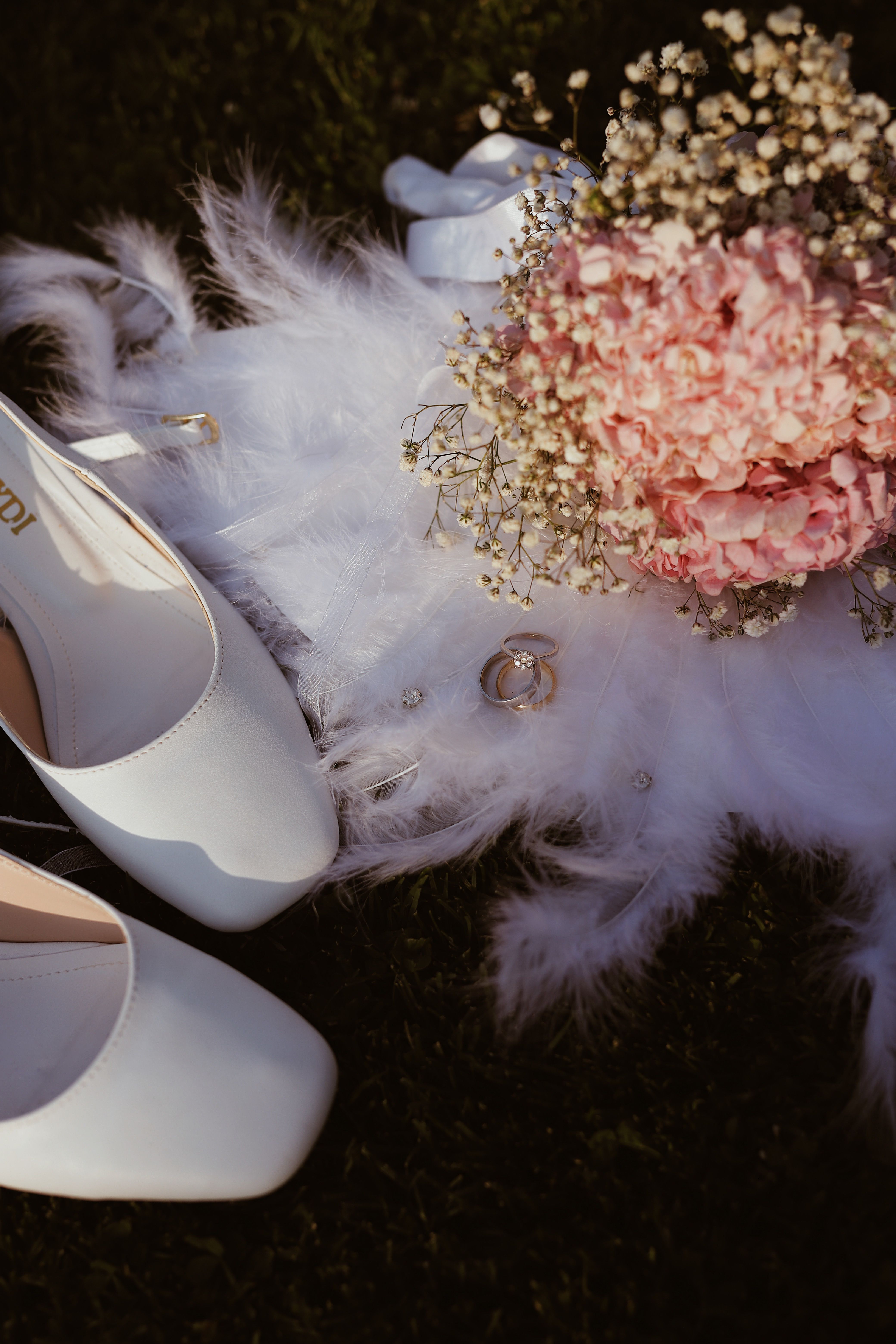 Flat lay of bridal shoes, rings and a pink hydrangea bouquet