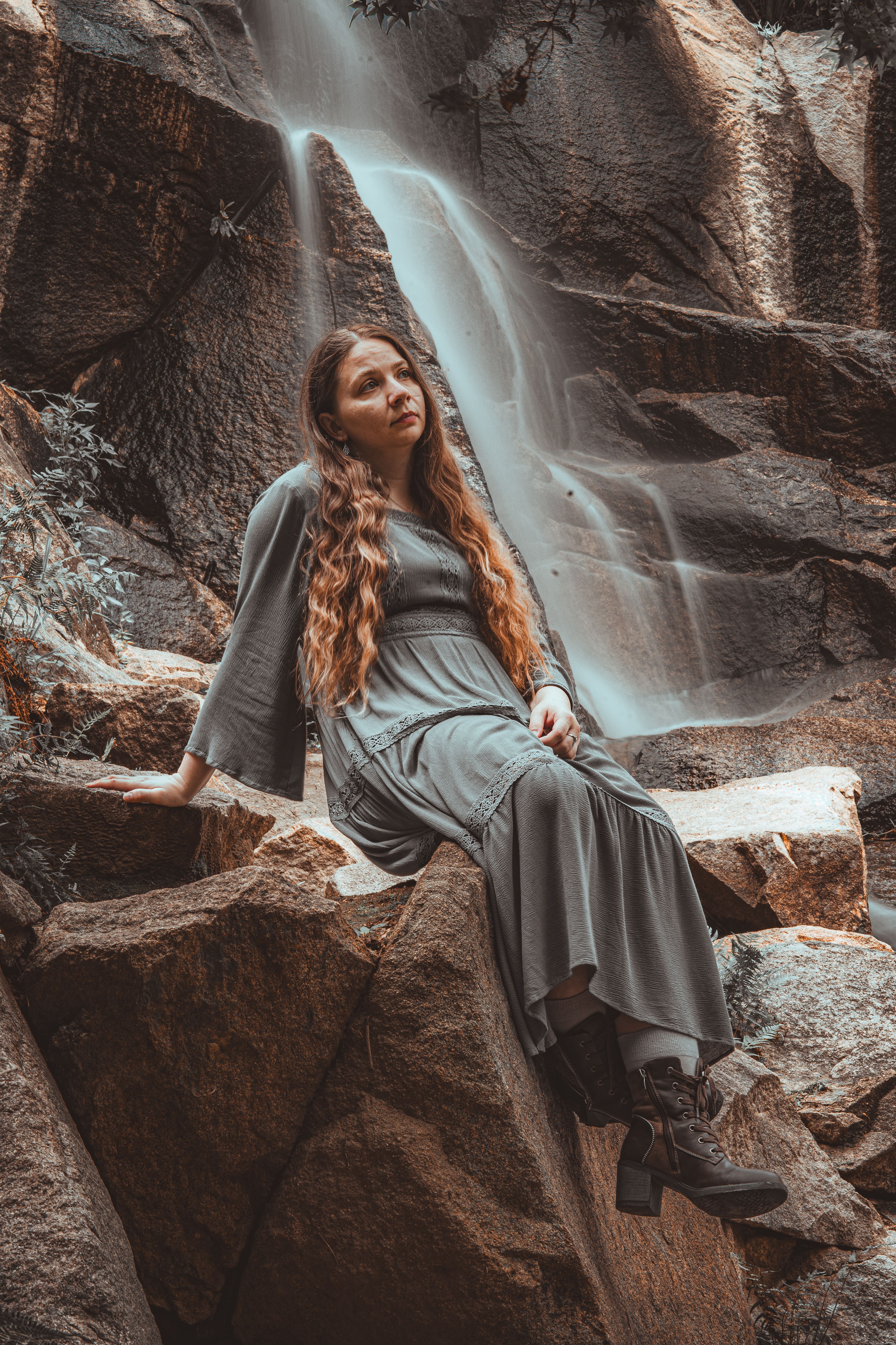 A woman sitting on a rock in front of a waterfall · Free Stock Photo