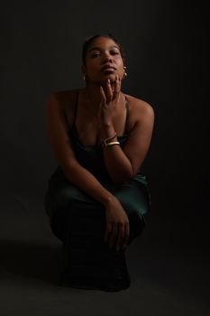 Striking studio portrait of a woman in elegant attire with dramatic lighting.