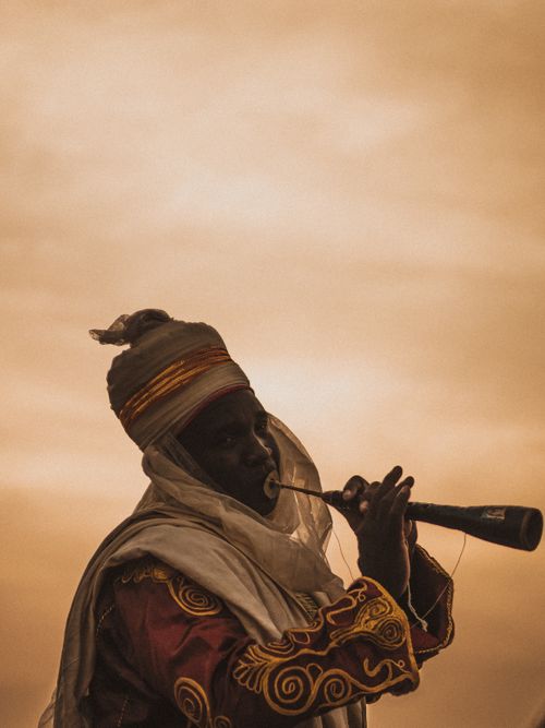 Free A musician in traditional attire playing the algaita in Nigeria at sunset. Stock Photo