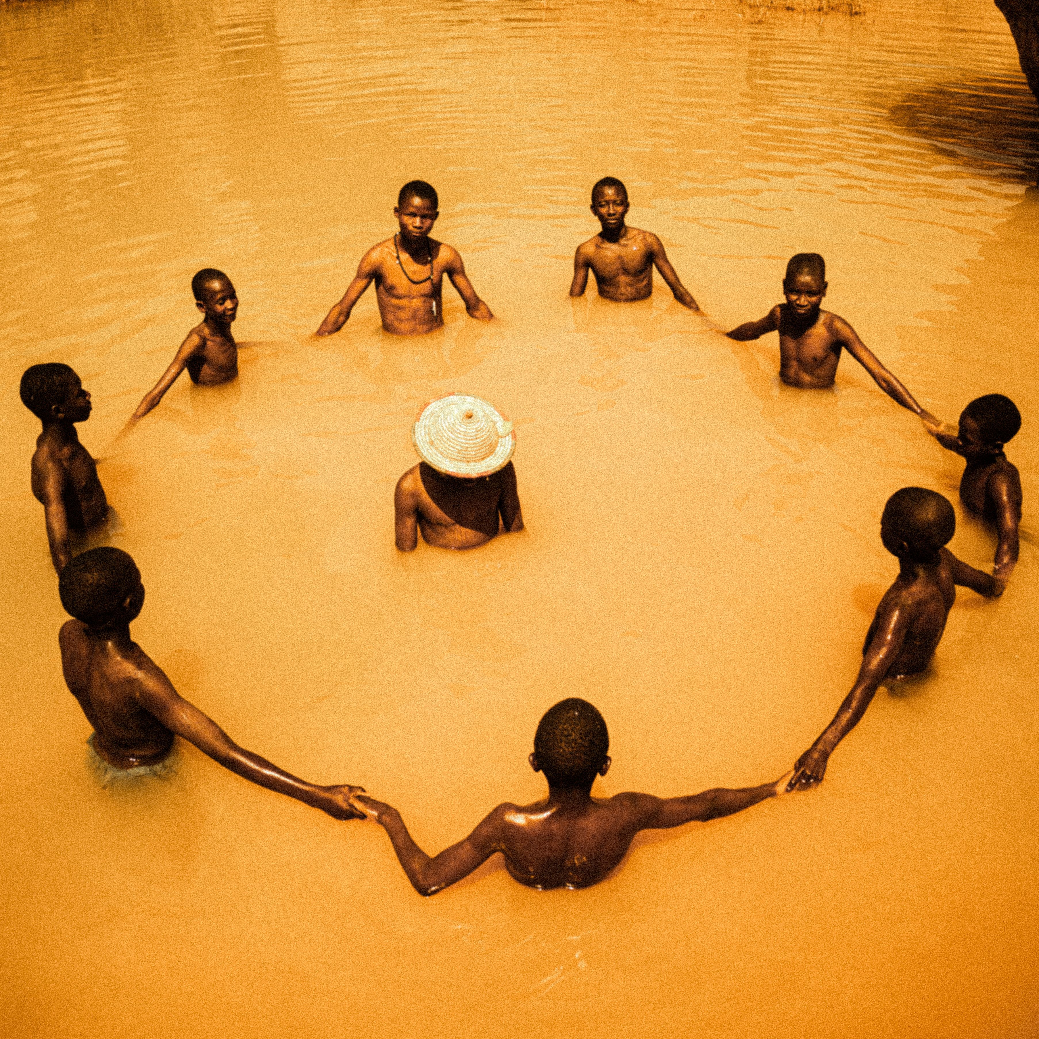 Group of children forming a circle, holding hands in a river in Nigeria.