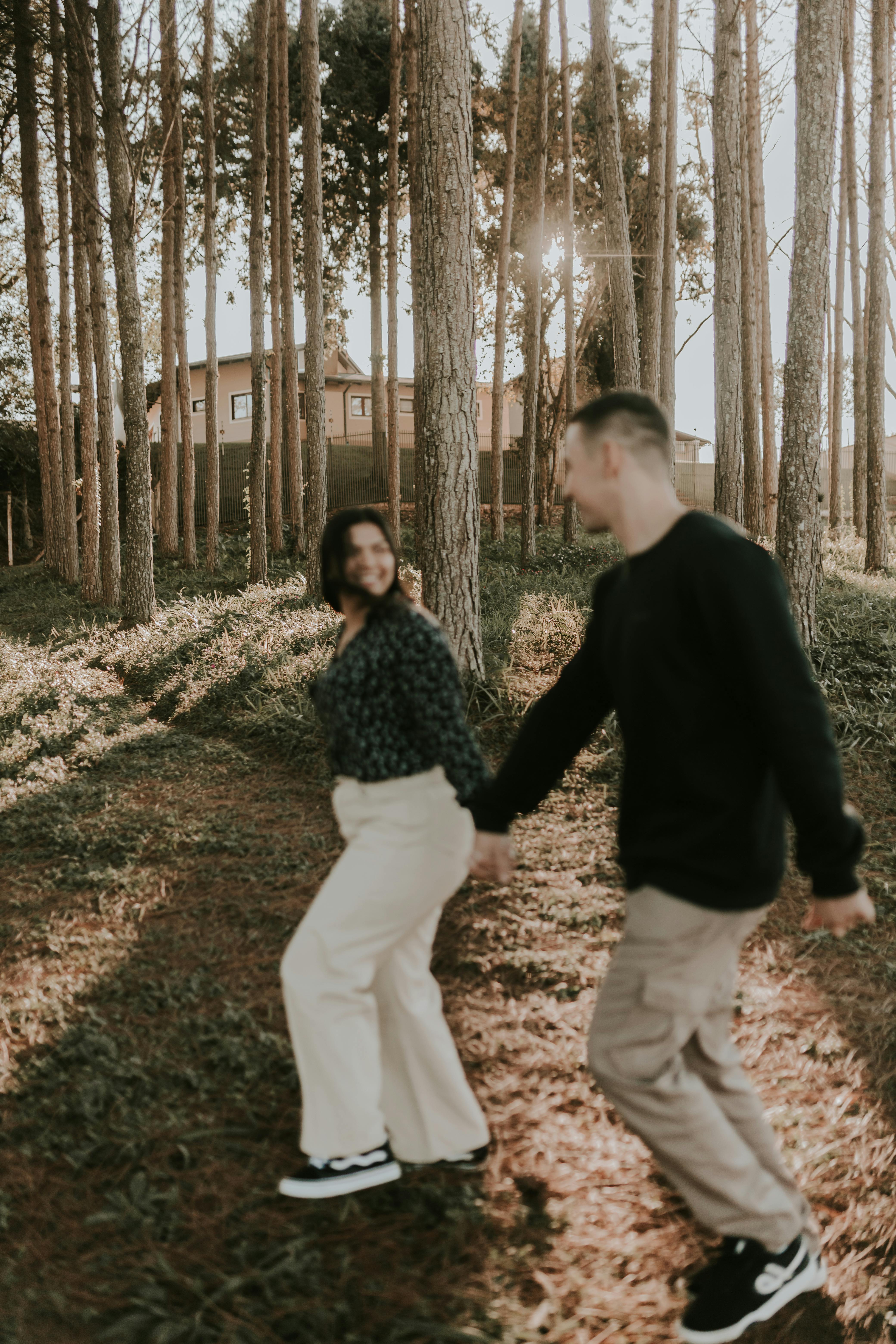 A joyful couple strolling through a sunlit forest path, capturing a moment of togetherness.