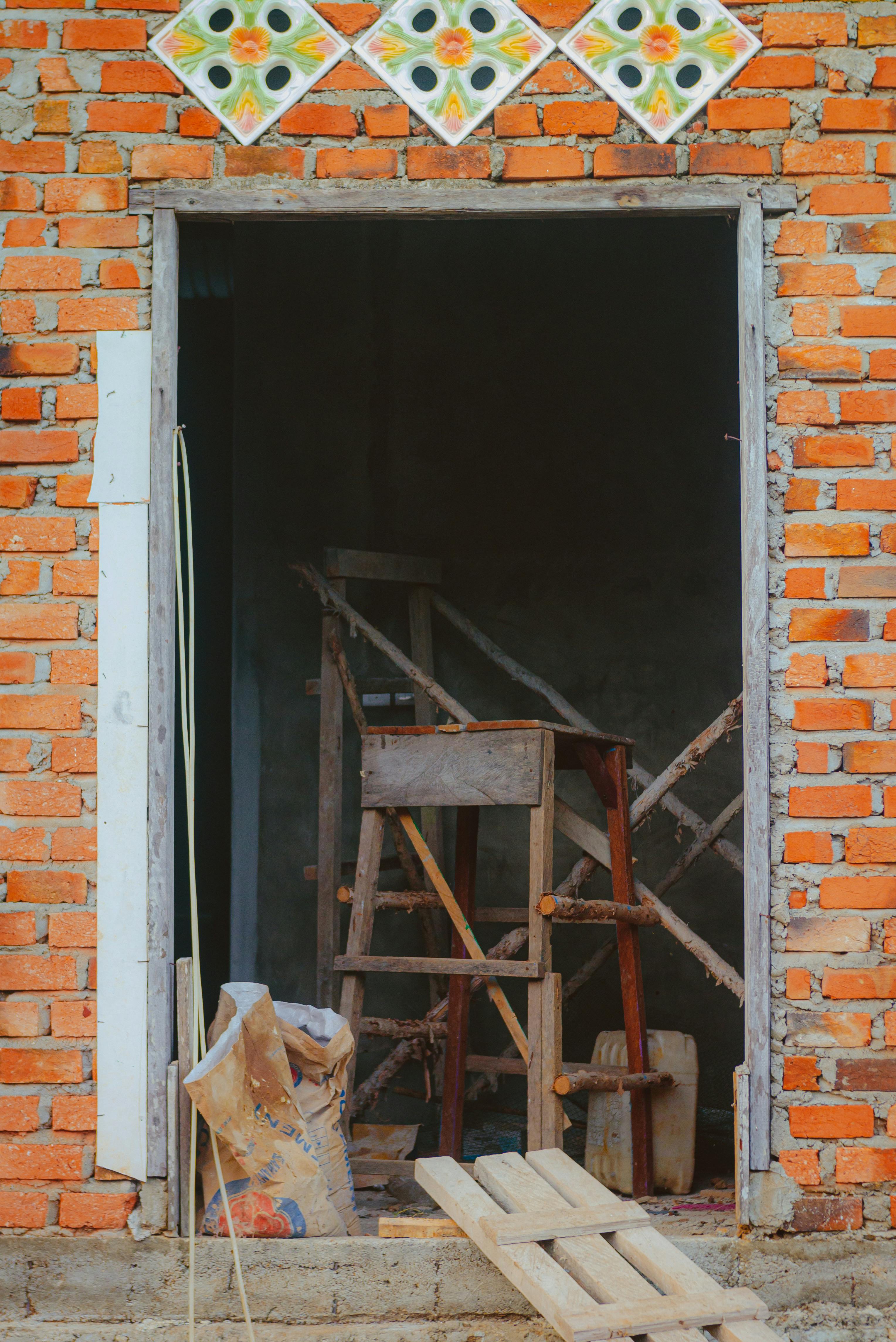 A view into an unfinished building with exposed brick walls and construction tools.