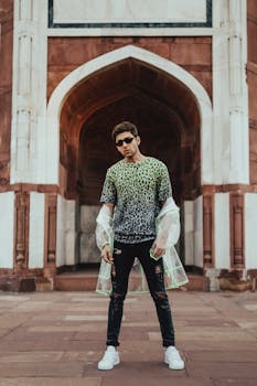 一位穿着豹纹透明雨衣的时尚男子，站在印度新德里一座历史悠久的拱门上