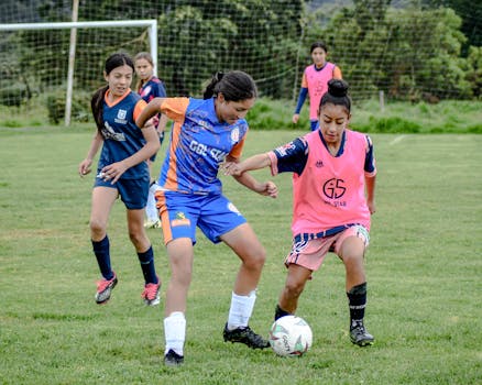 Energetic group of young girls playing soccer on a grassy field outdoors.