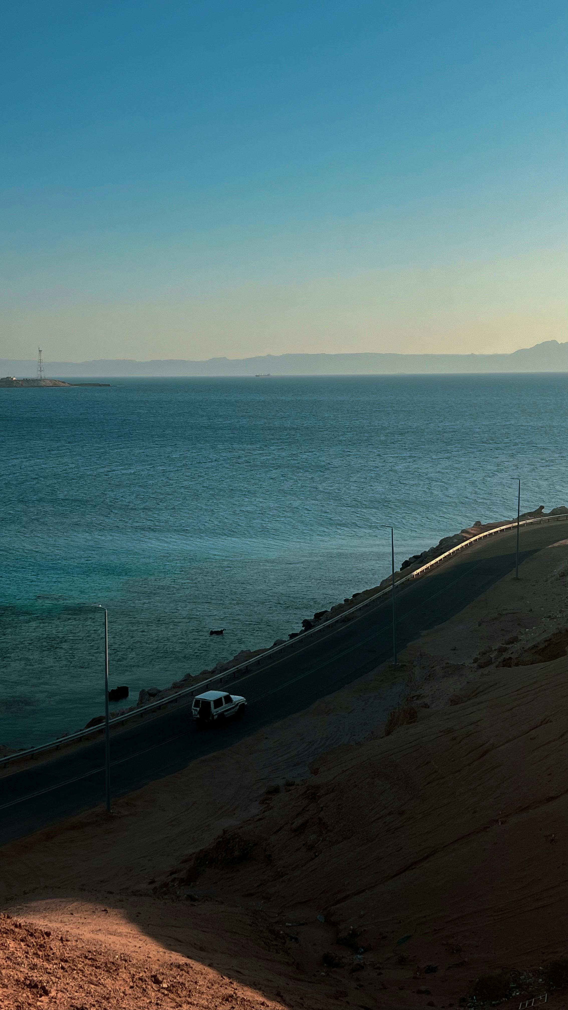 a car is driving along the shore of the sea