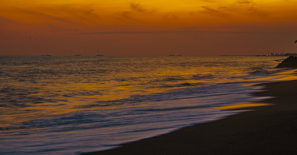 Golden hues of sunset over the tranquil Iztapa beach in Guatemala with gentle waves and evening sky.