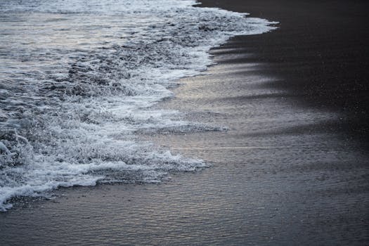 Tranquil ocean waves gently washing over sandy beach during a calming evening sunset.