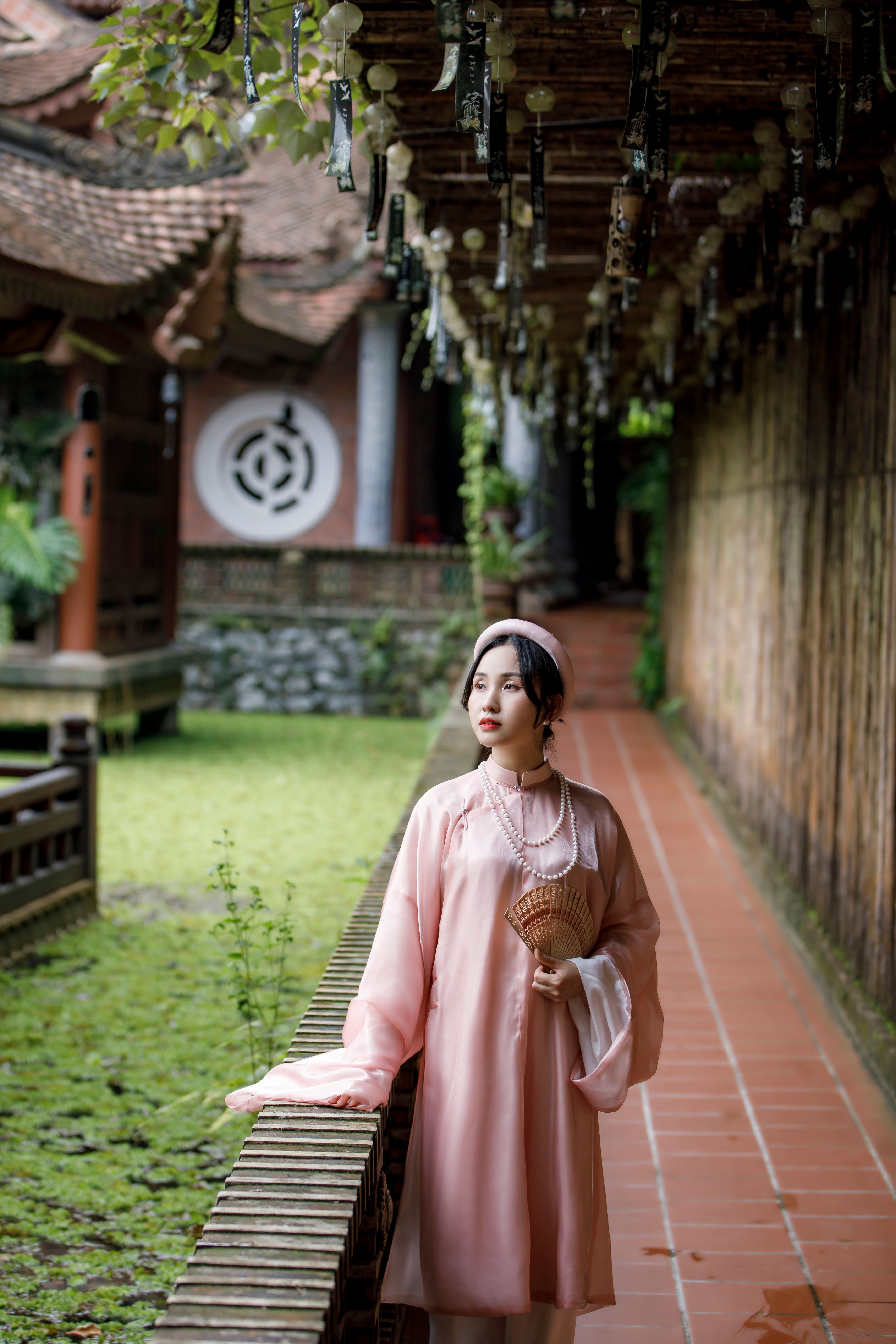 A woman in a pink dress stands in front of a wall · Free Stock Photo