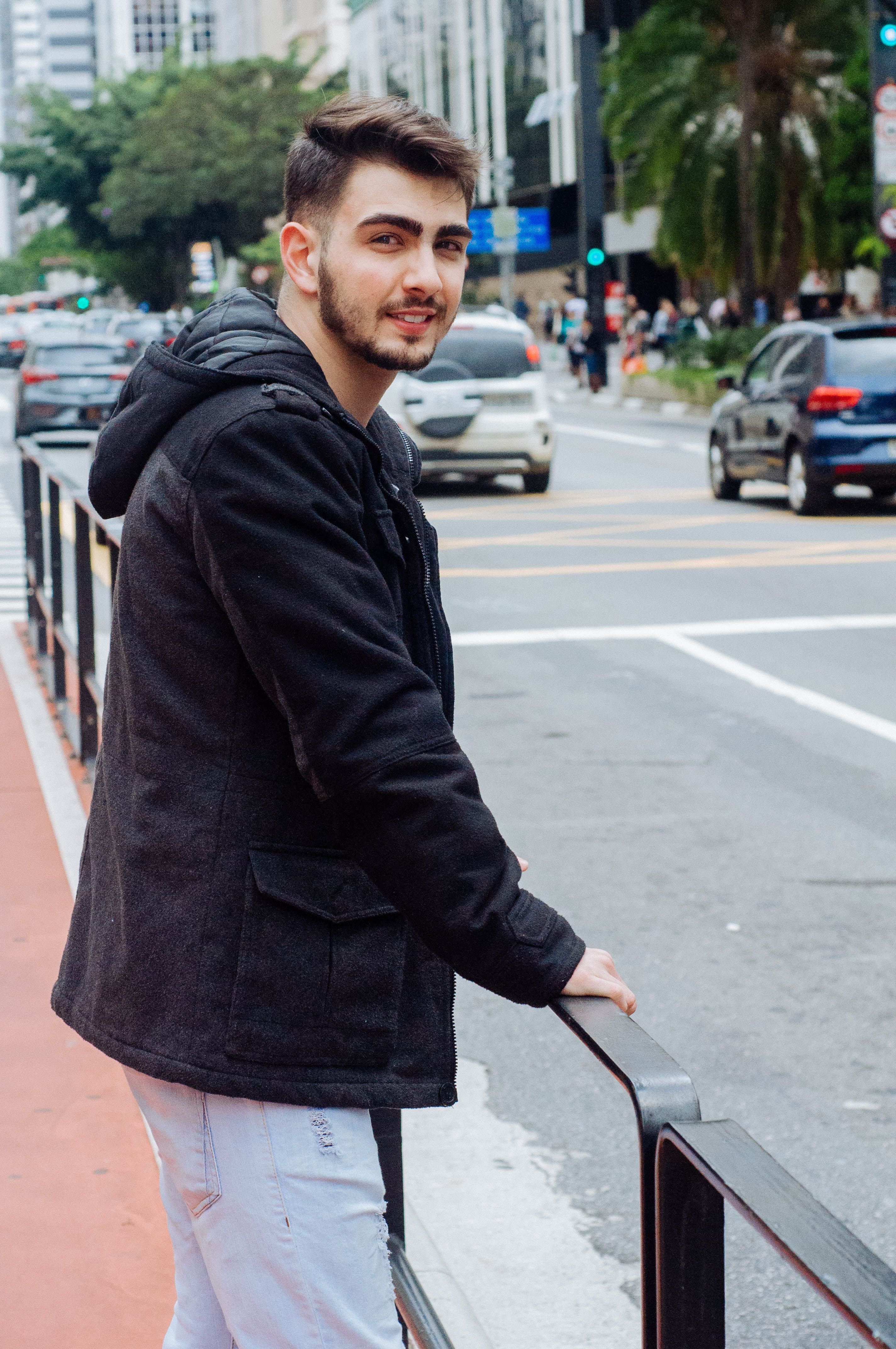A stylish man in a black jacket poses on Avenida Paulista, São Paulo, Brazil.