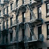 Classic New York City apartment buildings with fire escapes in an urban setting.