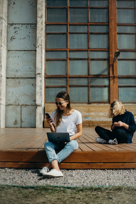 Strategies for Top Influencers: Mastering 10 Monetization Pathways in 2025 1 Two women working remotely on laptops outdoors, enjoying the sun. Perfect for freelance lifestyle themes.