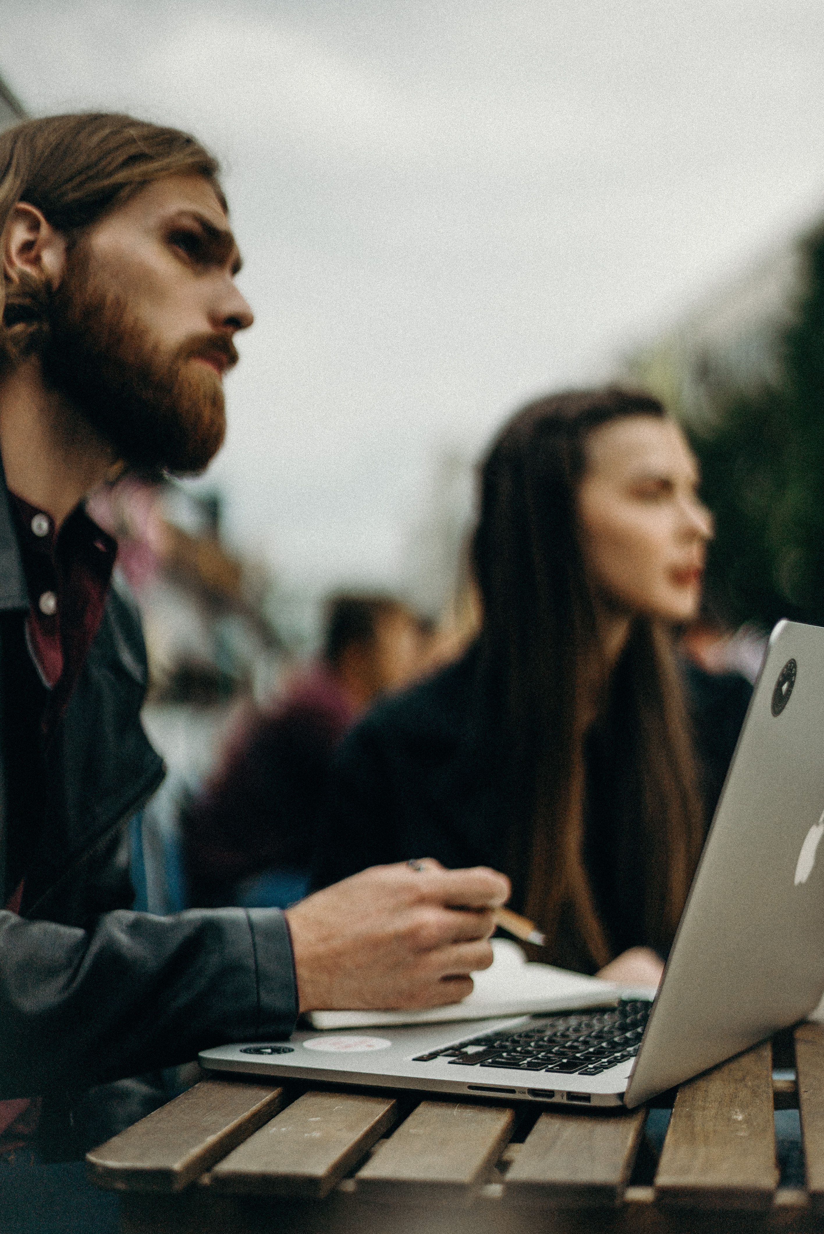 Person Using Macbook While Holding on Planner Book · Free Stock Photo