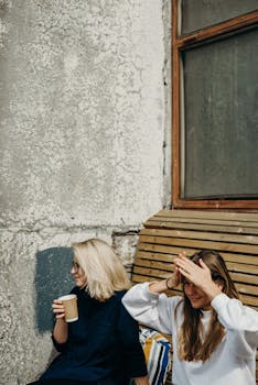 阳光明媚的日子里，两名年轻女子坐在城墙上，享受着户外咖啡