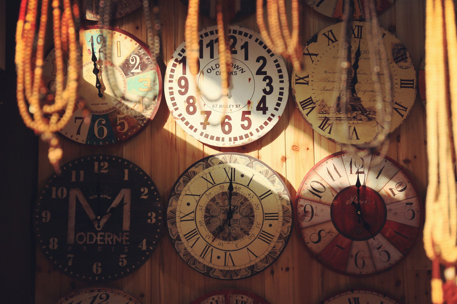 Collection of vintage wall clocks with unique designs on a wooden wall, creating a rustic decor vibe.